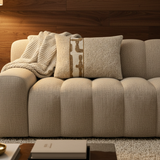 BRONS sierkussen Estoi oker stripe op een taupe bank met crème plaid