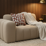 BRONS sierkussen Estoi brique op een taupe bank met crème plaid