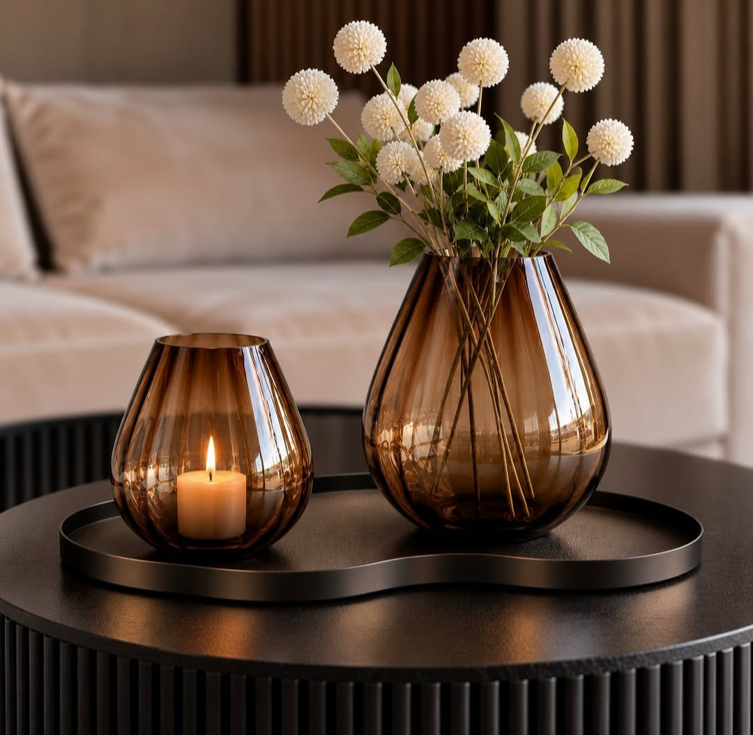 Tasman ribbed windlicht en vaas van VTW op een dienblad op een ronde salontafel, met een brandende kaars en witte bolbloemen