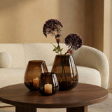 Drie Tasman windlichten in dark taupe glas van VTW met twee stelen Berenklauw Lavender op een walnoten salontafel