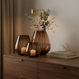 Set van 3 Tasman windlichten in dark taupe glas van VTW op een walnoten dressoir, met kaarsen en takken