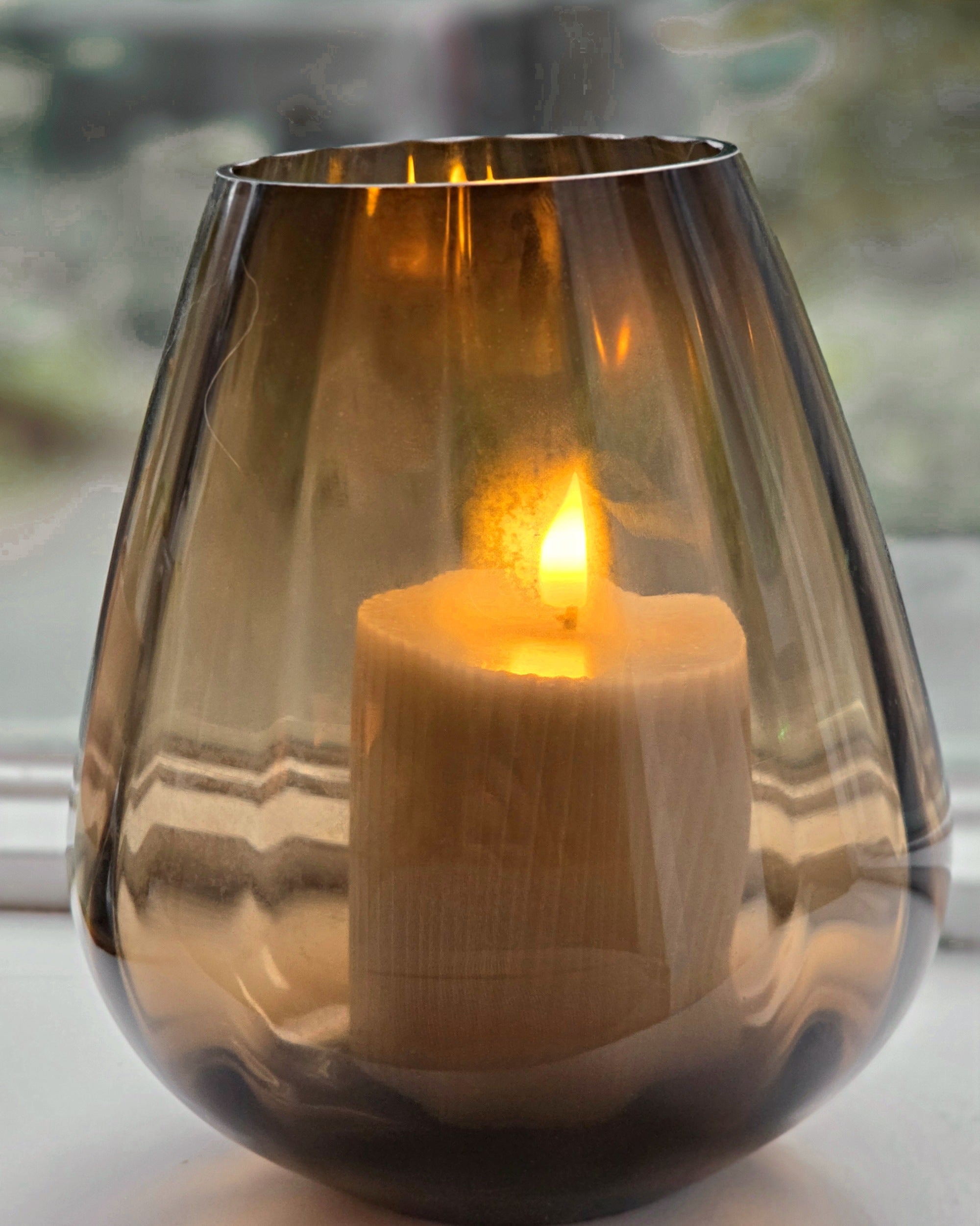 Tasman ribbed dark taupe van VTW met brandende kaars, de zachte ribbels in het rookglas van dichtbij