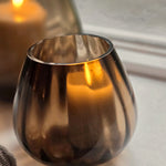 Kleine Tasman ribbed dark taupe met kaars, het licht schijnt gestreept door het glas